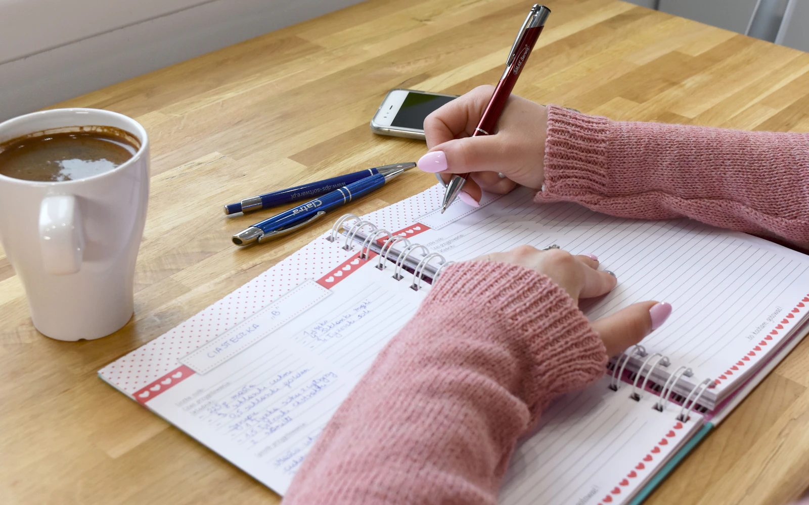 Personne écrivant dans un carnet à côté d'une tasse de café — atelier minimal